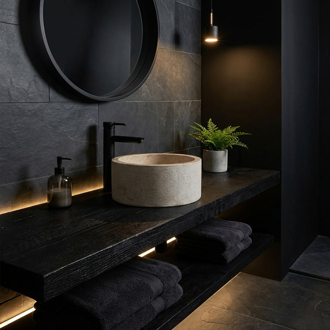 Lavabo à poser rond au look marbre élégant sur une console en bois sombre, mis en scène dans une salle de bain minimaliste à l'ambiance sombre.