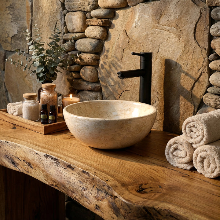 Lavabo en pierre claire en fixation sur une console en bois massif avec robinetterie noire dans une ambiance naturelle de salle de bain spa