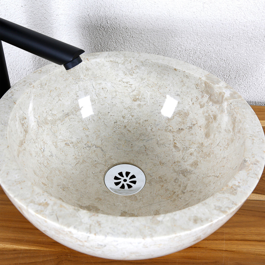 Gedetailleerde weergave van een ronde opzetwastafel van licht natuursteen met een gepolijst binnenoppervlak en centrale afvoer