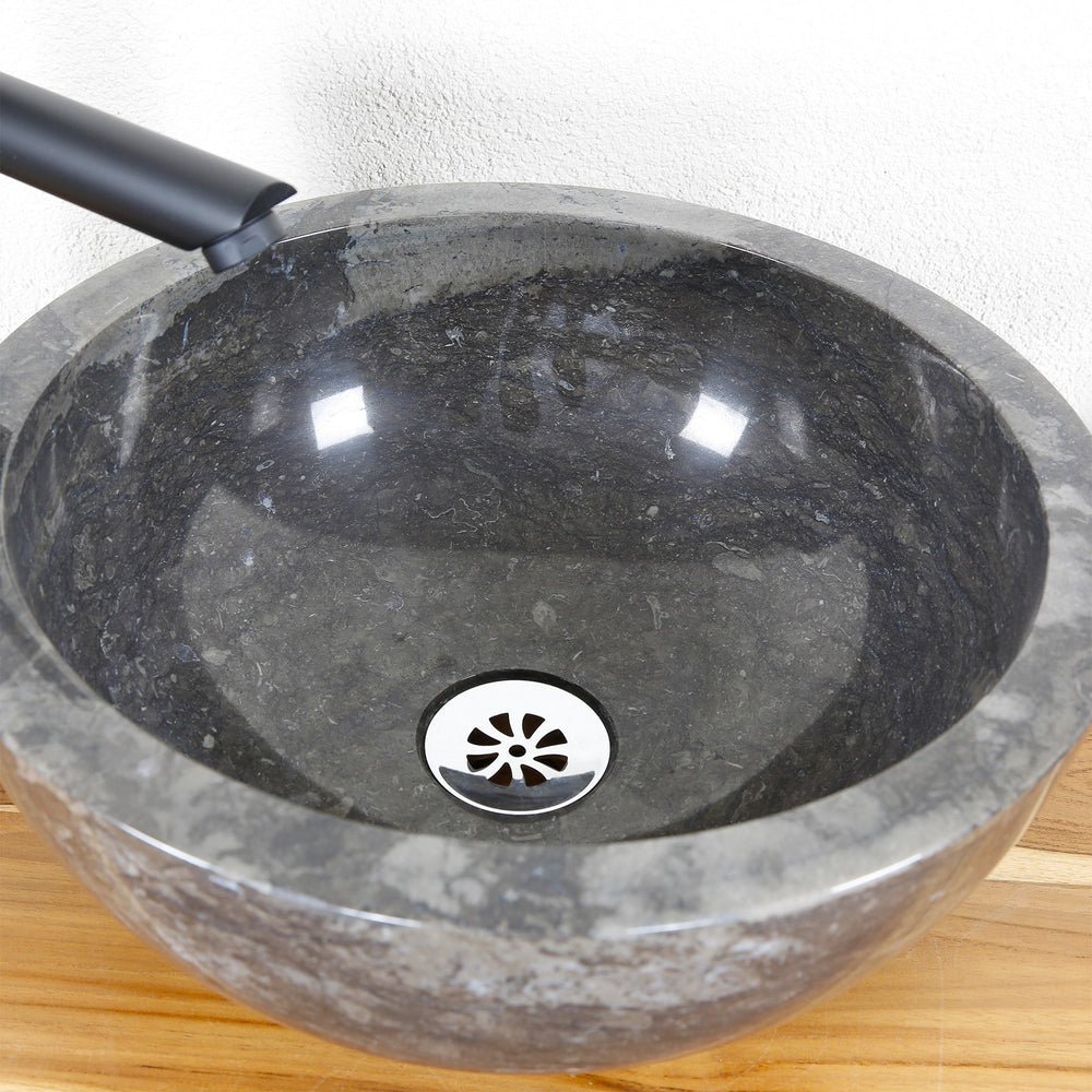 Gedetailleerd aanzicht van een rond stenen bassin met een gepolijst binnenoppervlak en een centrale afvoer op een houten plaat