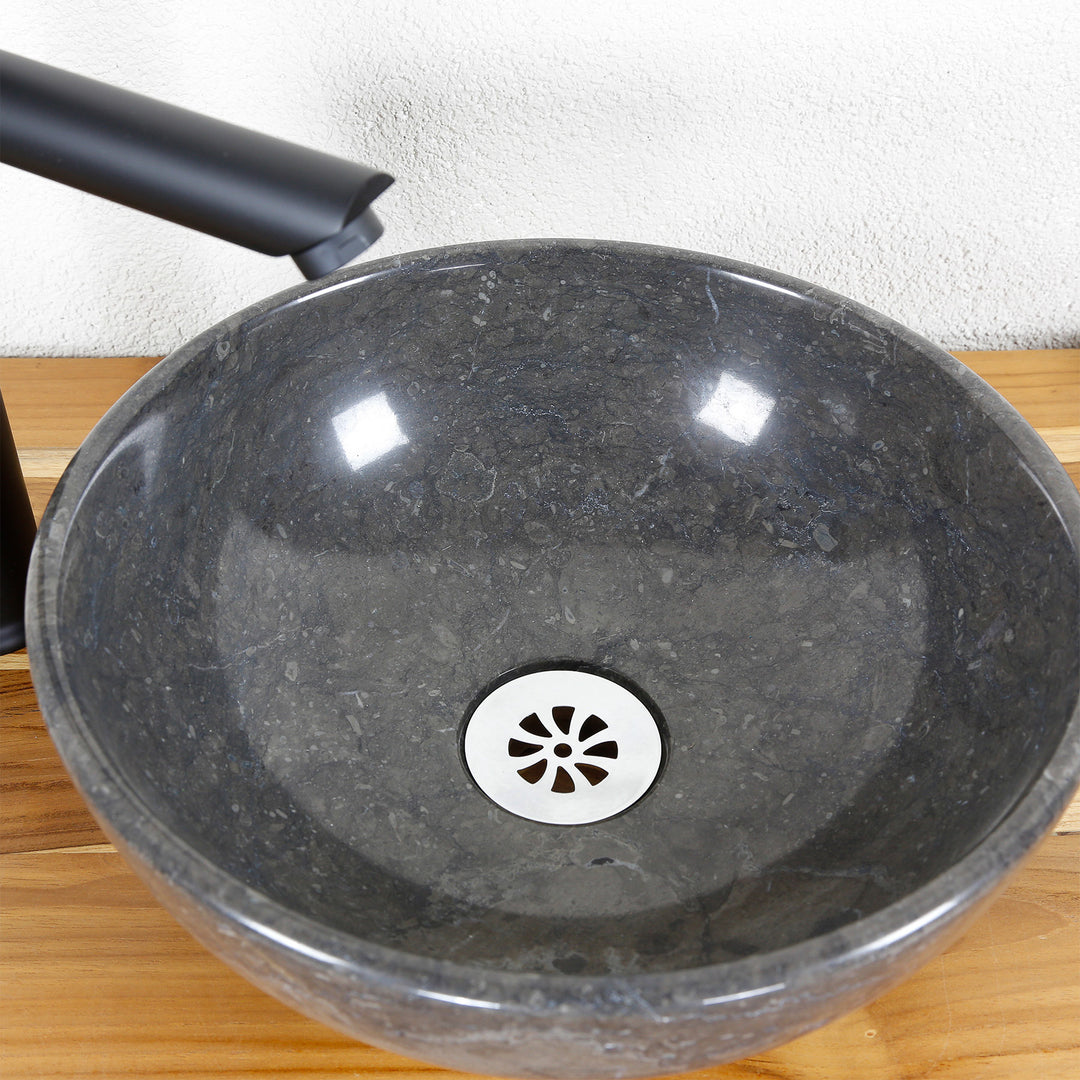 Vasque à poser ronde en pierre naturelle en détail avec surface intérieure polie, vidage et robinetterie en acier inoxydable