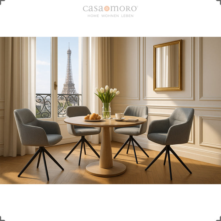 Quatre chaises rembourrées pivotantes à 360° avec accoudoirs gris autour d'une table ronde en bois dans une élégante salle à manger avec vue sur la Tour Eiffel