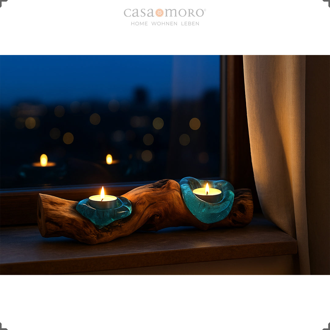 Langwerpige theelichthouder van glas en wortelhout op een vensterbank, het warme licht gloeit zachtjes in de avondsfeer.