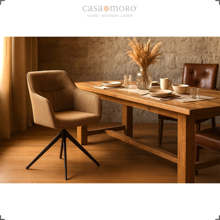 Chaise rembourrée rotative à 360° avec accoudoirs marron sur une table en bois avec un mur en pierre naturelle, une table dressée et une lumière chaude