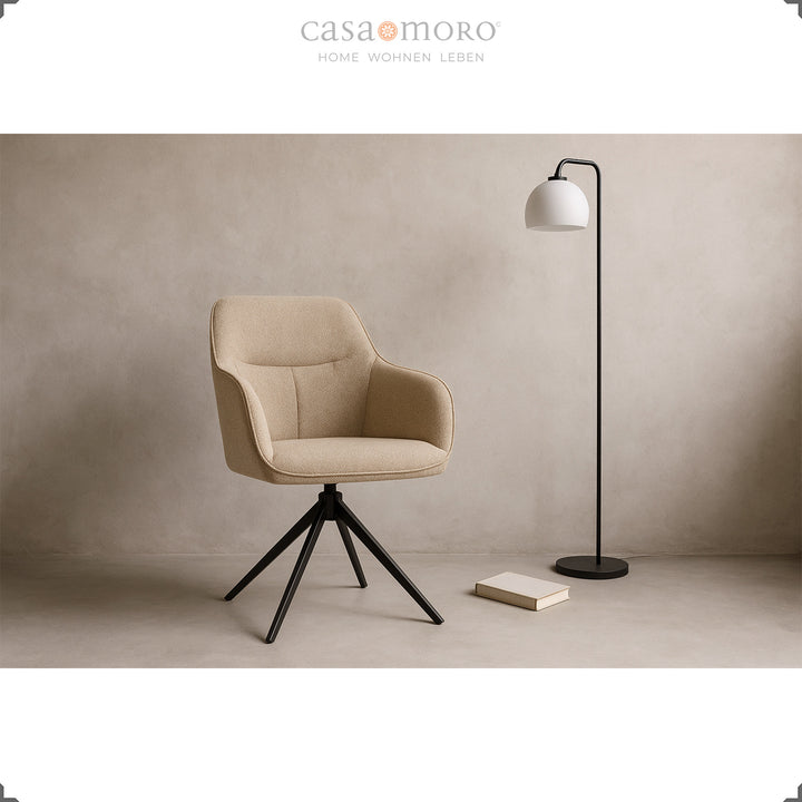 Chaise moderne rembourrée rotative à 360° avec accoudoirs beige, mise en scène dans le salon avec un lampadaire noir et un livre sur un sol clair