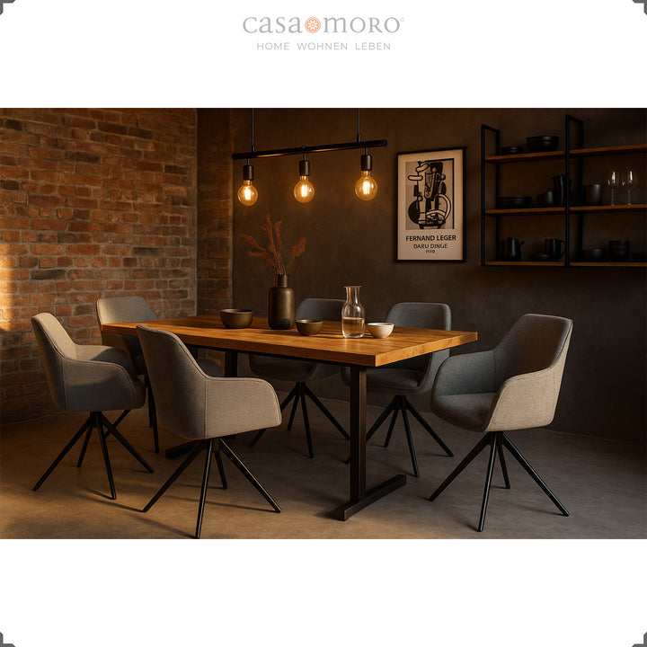 Six chaises rembourrées grises pivotantes à 360° avec accoudoirs sur une table en bois dans une salle à manger moderne avec un mur de briques et un éclairage d'ambiance