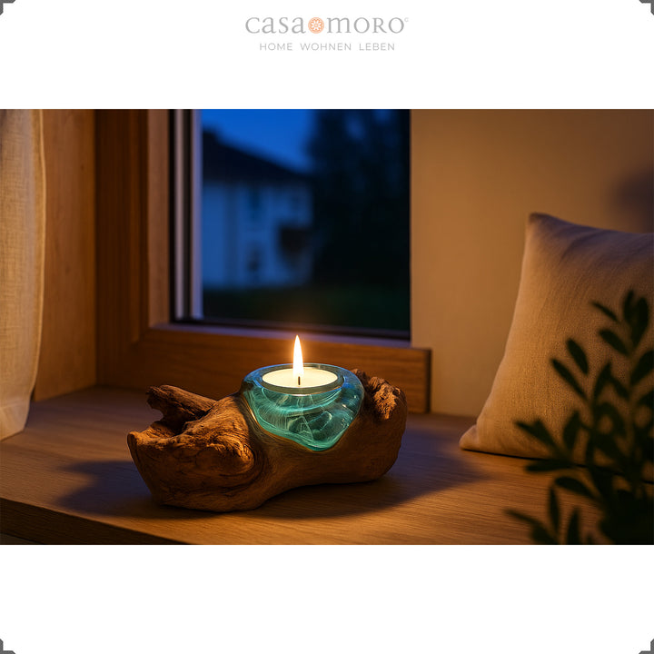 Theelichthouder van glas en wortelhout op een vensterbank, het warme licht zorgt 's avonds voor een zachte, rustgevende sfeer.