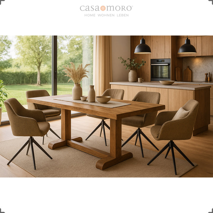 Quatre chaises rembourrées marron pivotantes à 360° avec accoudoirs autour d'une table en bois dans une cuisine moderne avec de grandes fenêtres et une vue sur la campagne