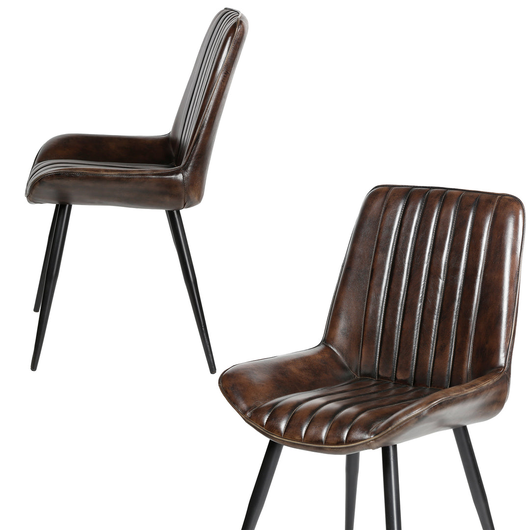 Antieke bruinleren stoelen met verticale quilting, zijwaarts en diagonaal gefotografeerd, op zwart gelakte metalen poten