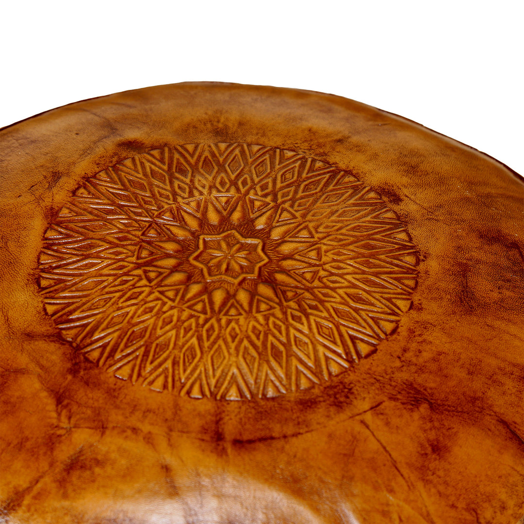 Vue détaillée du dessus gaufré d'un pouf en cuir marron chaud avec un fin motif oriental et une structure en cuir naturel.