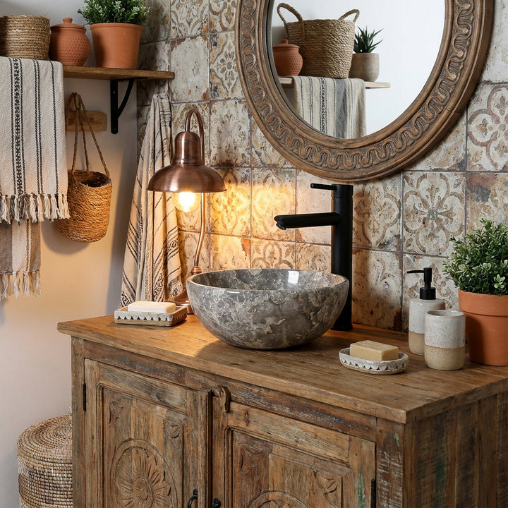 Lavabo rond en marbre avec grain gris sur lavabo en bois rustique dans une salle de bains confortable, combiné avec des raccords noirs, des carreaux à motifs et un éclairage chaleureux