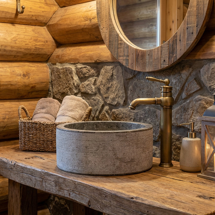 Marbre rondLavabo sur une console rustique en bois avec des raccords en laiton dans la salle de bain confortable du chalet, chaleureusement éclairée.