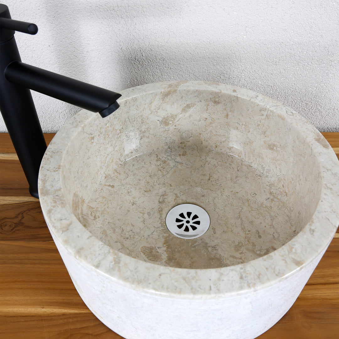 Vue détaillée d'un lavabo à poser rond d'aspect marbre clair avec une surface intérieure lisse et un écoulement fin.