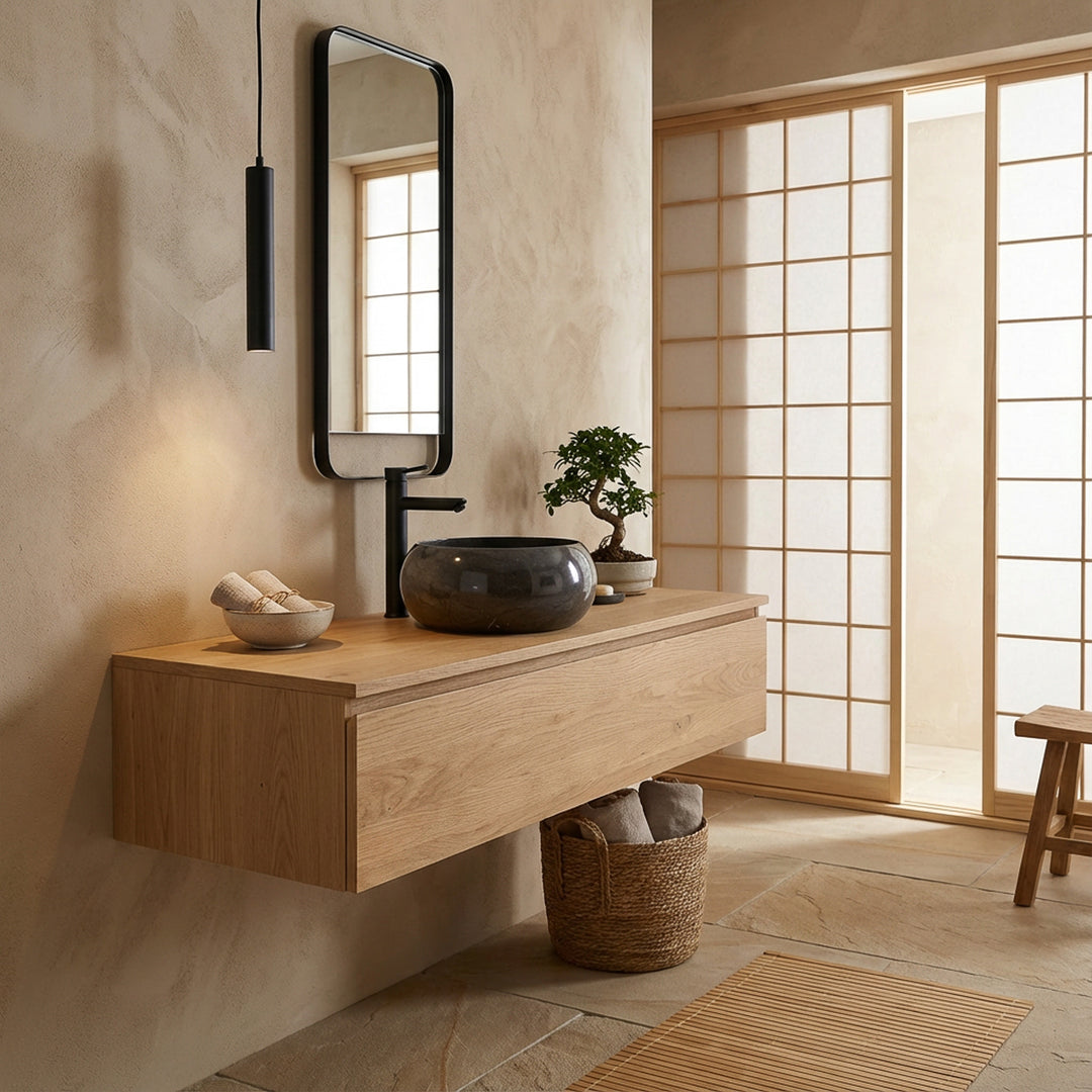 Ronde stenen wastafel op zwevend houten meubel in Japans geïnspireerde badkamer, gecombineerd met zwarte fittingen, spiegel met houten frame en zacht natuurlijk licht