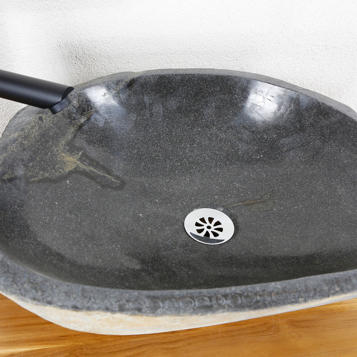 Gedetailleerd aanzicht van een stenen wastafel met een fijn gepolijst binnenoppervlak, natuurlijke nerven en een centrale afvoer