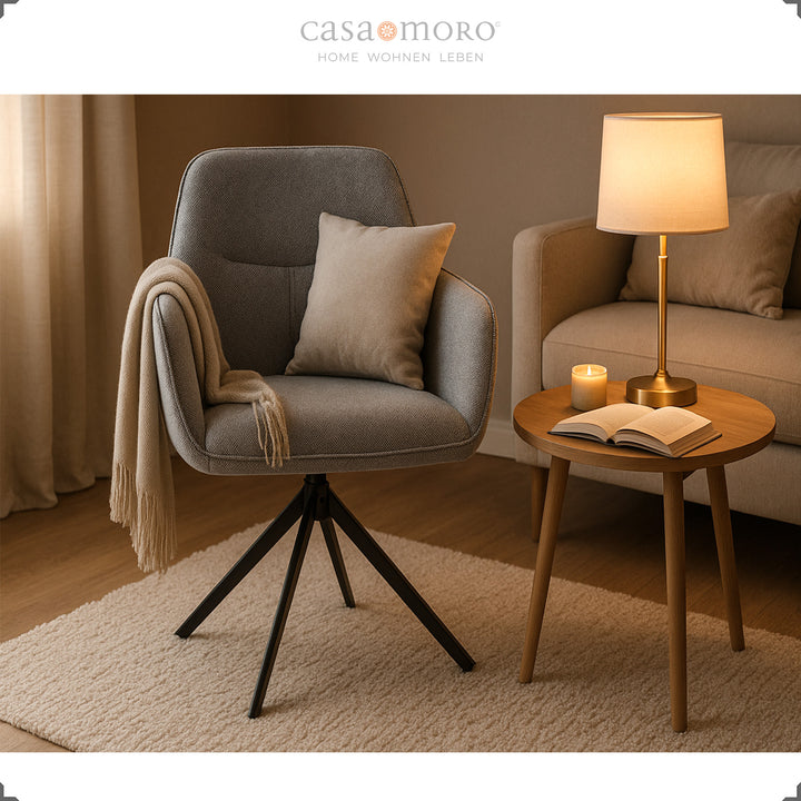 Chaise rembourrée rotative à 360° avec accoudoirs gris, confortablement disposée à côté d'une table d'appoint, d'une lampe et d'un canapé dans un salon moderne 