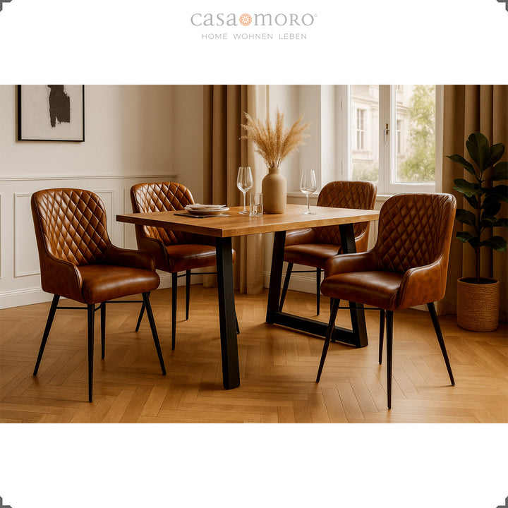 Vier antieke bruinleren stoelen met diamantquilt aan een houten tafel in een elegante eetkamer met parketvloer, lichte lambrisering en natuurlijke decoraties.