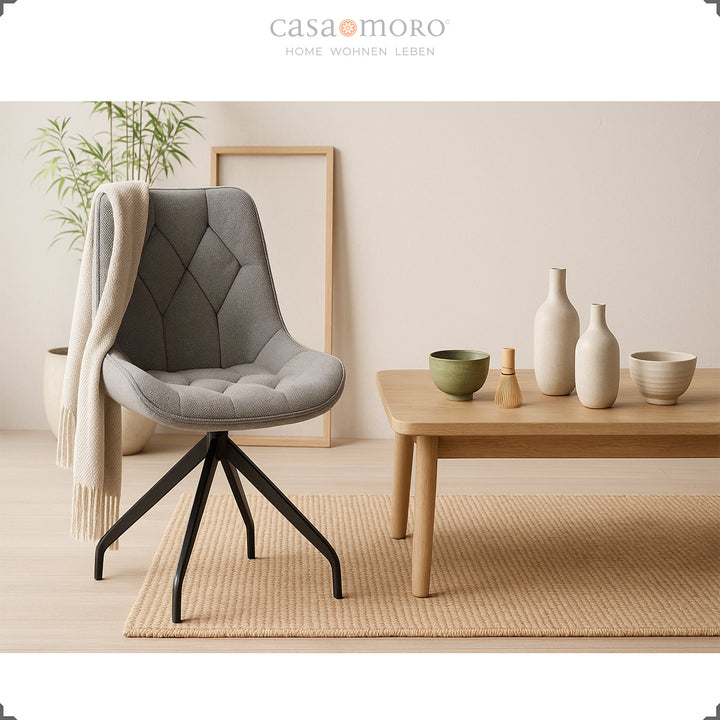 Chaise rembourrée grise avec fonction pivotante à 360° et structure en métal noir - chaise d'appoint moderne à côté d'une table en bois avec décoration en céramique dans une ambiance de vie naturelle