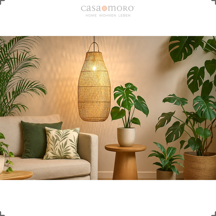 Große Rattan Deckenleuchte über Sofa im Wohnzimmer mit vielen Grünpflanzen und warmem Licht