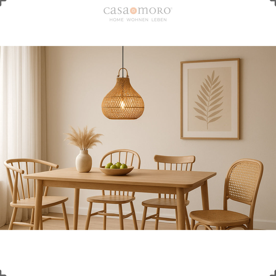 Lampe suspendue en rotin au-dessus de la table à manger dans une salle à manger lumineuse avec une décoration naturelle et une lumière chaude