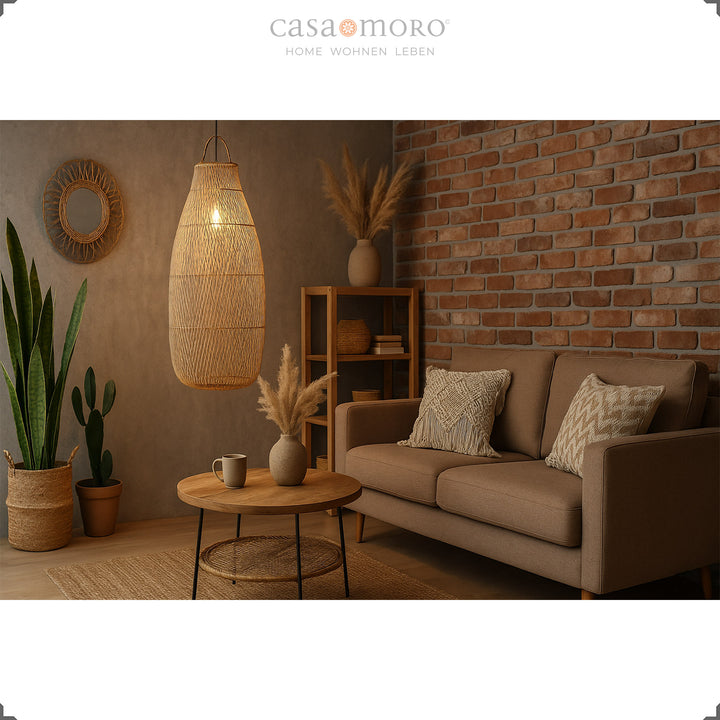 Hohe, hängende Rattanlampe im Wohnzimmer mit Backsteinwand und warmem Lichtspiel