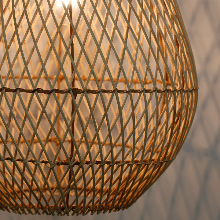 Photo détaillée d'une lampe en rotin faite à la main avec un motif de tissage fin en diagonale et une lumière chaude