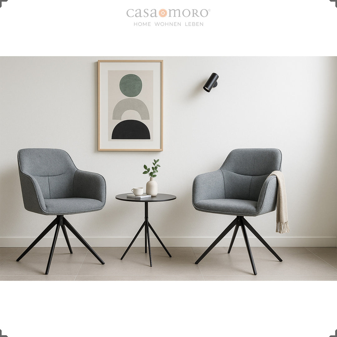 Deux chaises rembourrées pivotantes à 360° avec accoudoirs gris à côté d'une table d'appoint ronde dans un salon moderne avec une décoration murale lumineuse