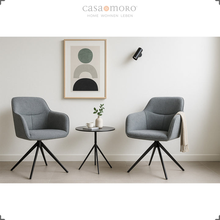 Deux chaises rembourrées pivotantes à 360° avec accoudoirs gris à côté d'une table d'appoint ronde dans un salon moderne avec une décoration murale lumineuse