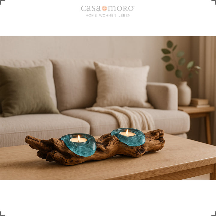 Theelichthouder van glas en wortelhout op een salontafel, het warme licht complementeert de heldere, gezellige sfeer in de woonkamer.