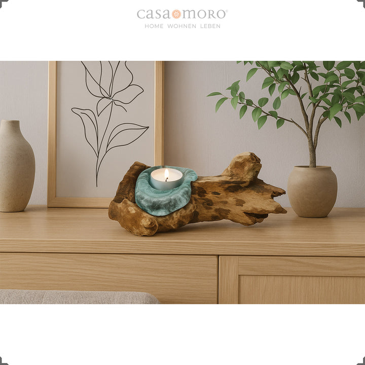 Theelichthouder van glas en wortelhout op een dressoir, het warme licht complementeert de natuurlijke, eenvoudige woonkamerdecoratie.