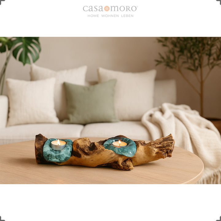 Theelichthouder van glas en wortelhout op een ladekast, het warme licht complementeert het eenvoudige, natuurlijke ontwerp van de kamer.