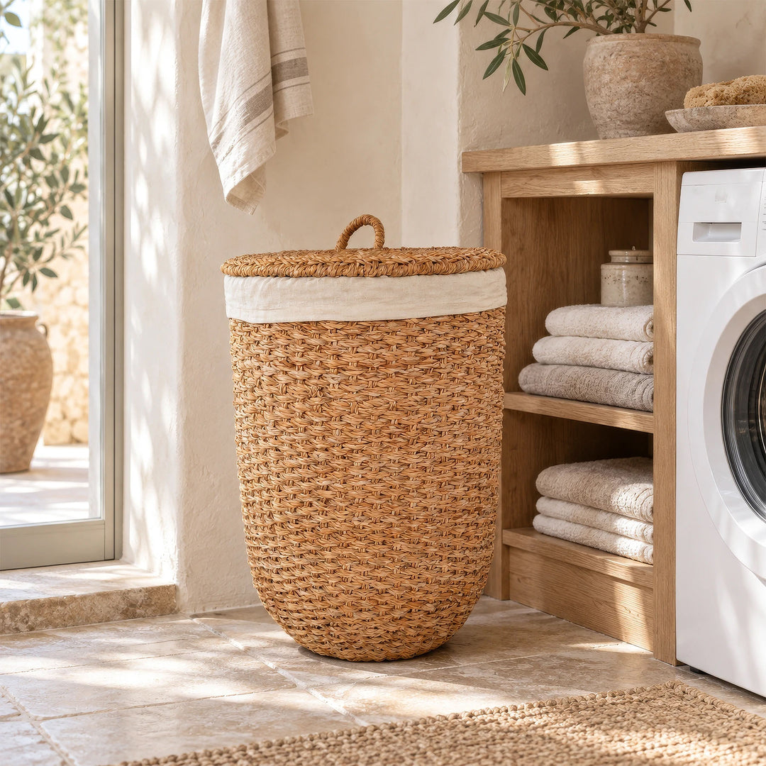 Un panier à linge avec couvercle, en jonc de mer de couleur naturelle, à côté d'un porte-serviettes et d'un lave-linge dans la buanderie.