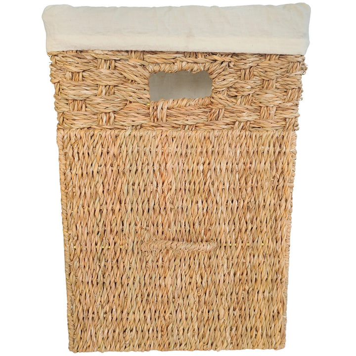 Panier à linge carré en jonc de mer, bord de sac clair et couvercle rectangulaire tressé appuyé devant.