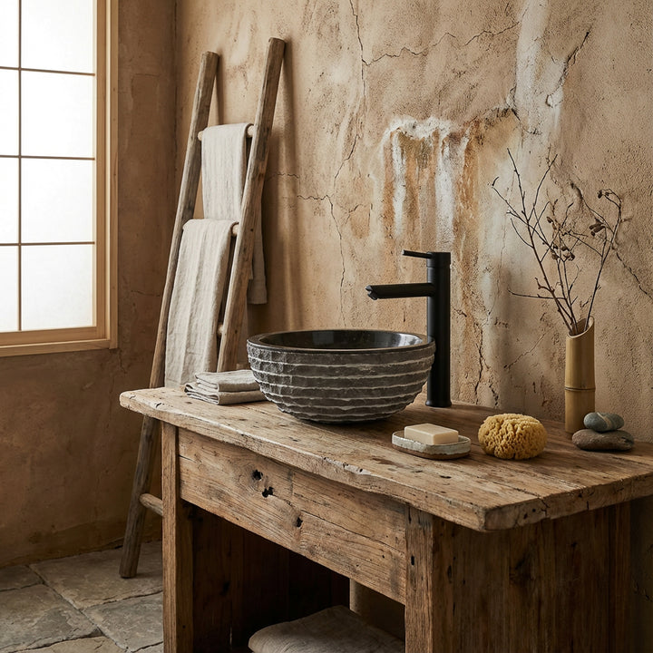 Lavabo rond en pierre naturelle sur table en bois rustique dans une salle de bains spa tranquille avec robinet noir et lumière naturelle chaude