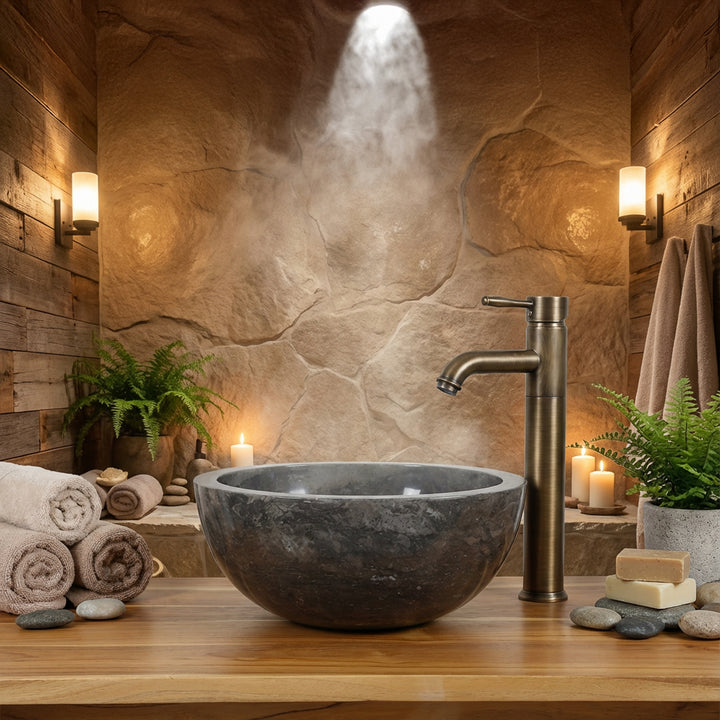 Ronde stenen wastafel gemonteerd op een houten console met messing beslag in een warme spa-badkamersfeer